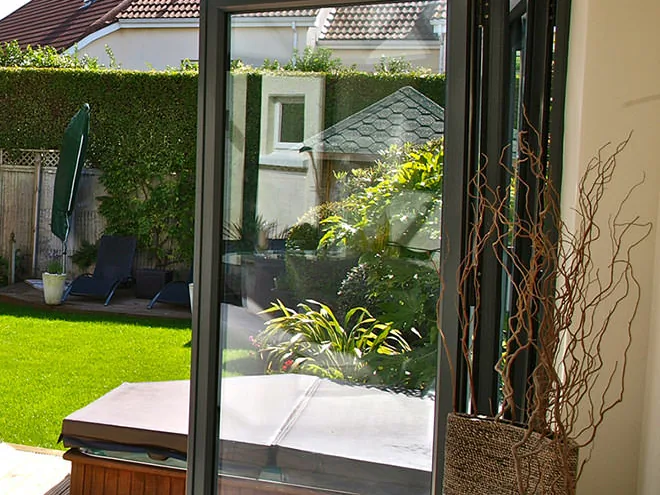Close view of a dark-framed bifold door leaf opening onto a garden
