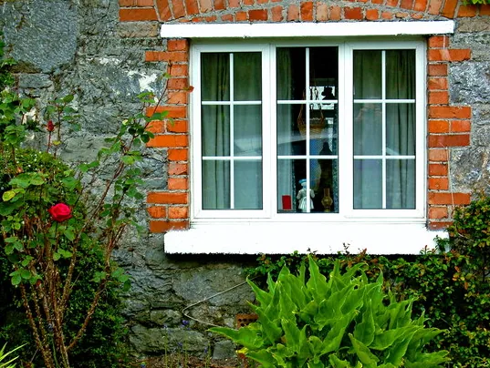 White casement window with glazing bars in a stone and brick wall